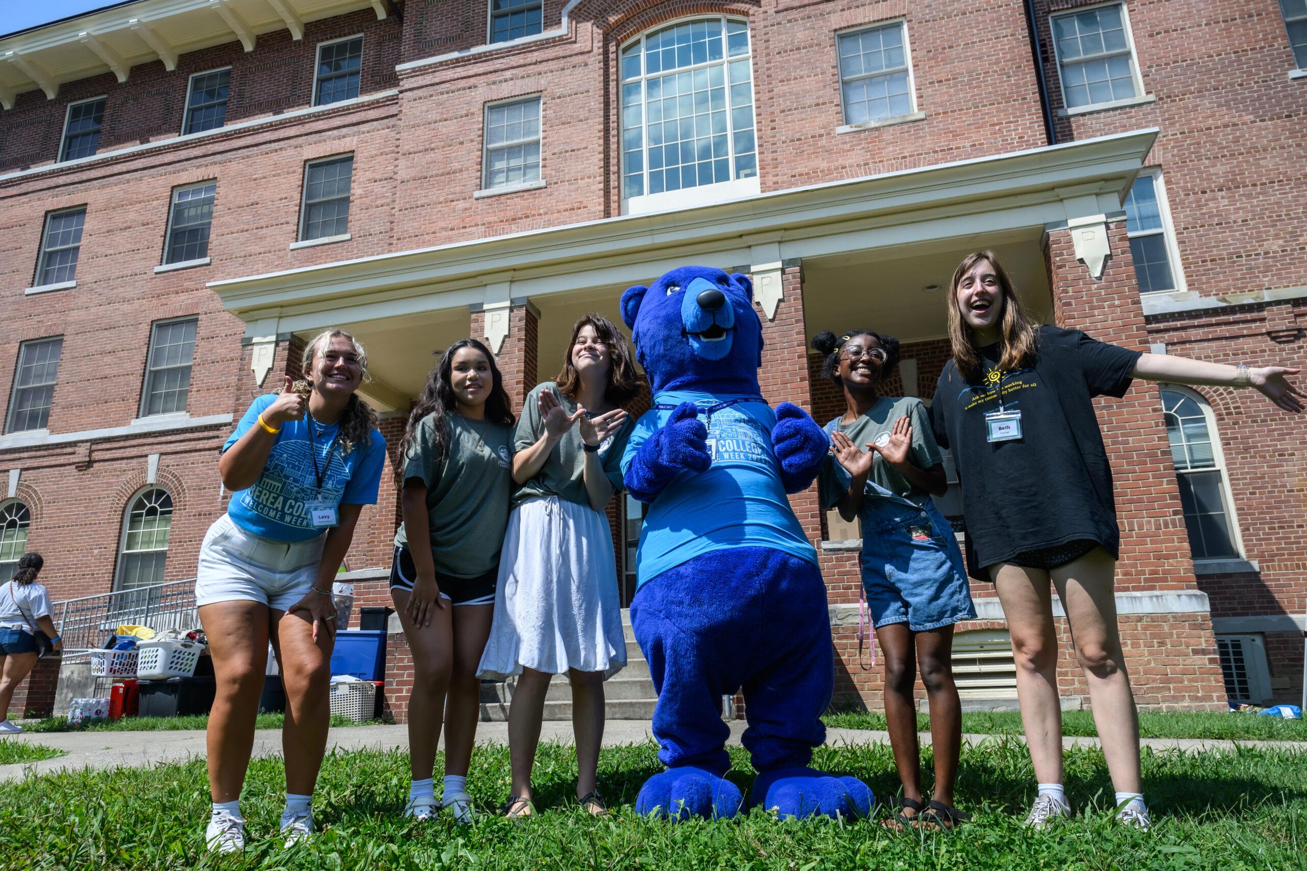 Blue the Bear and five new first-year students in front of Pearson Hall.